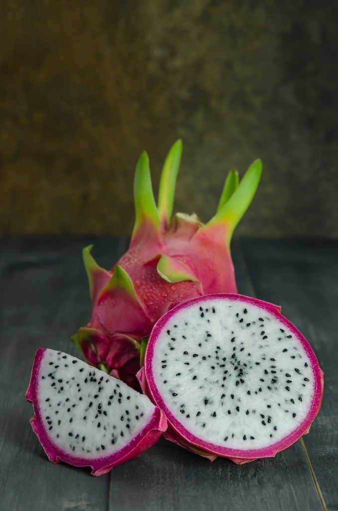 a dragon fruit cut in half on a wooden table