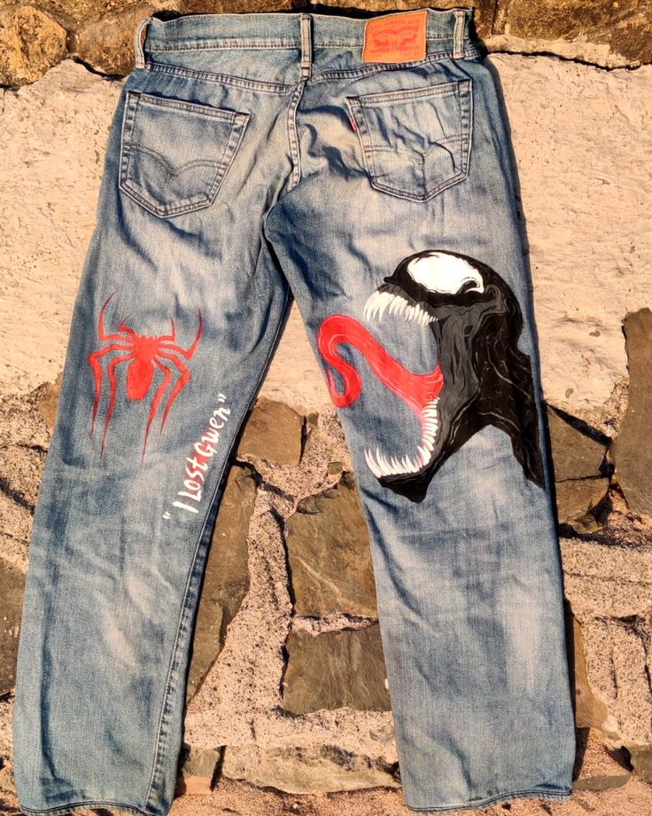 a pair of jeans with an image of a spider man on them, sitting against a stone wall