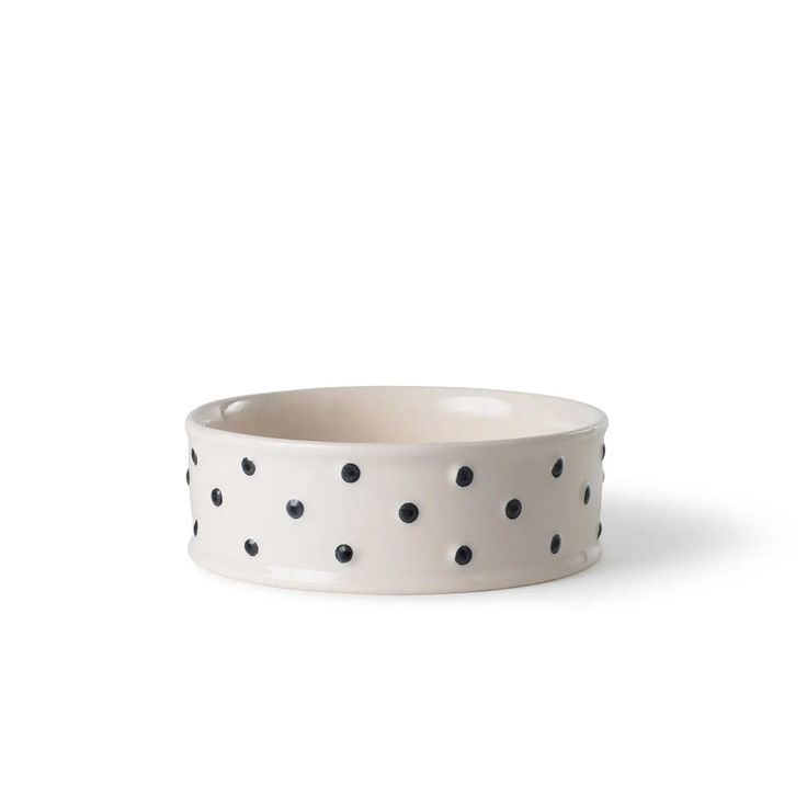 a white bowl with black polka dots on the outside and inside, sitting in front of a white background