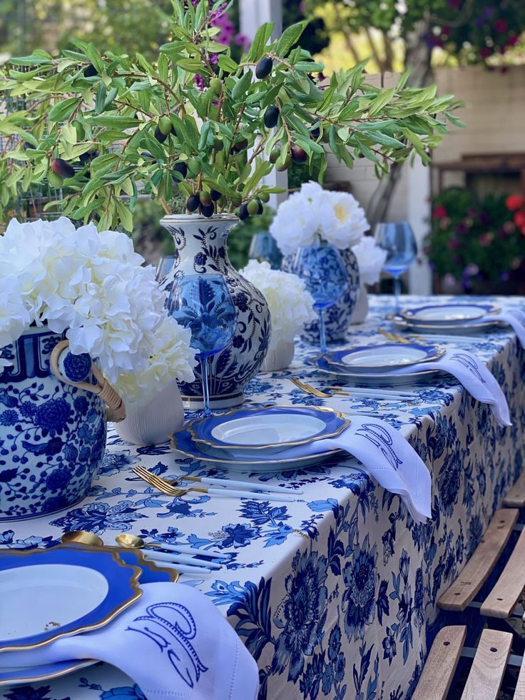 the table is set with blue and white plates, flowers in vases, and napkins