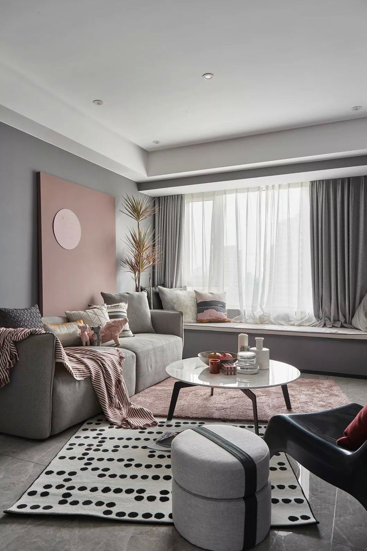 a living room filled with furniture and a large window covered in curtains next to a white rug