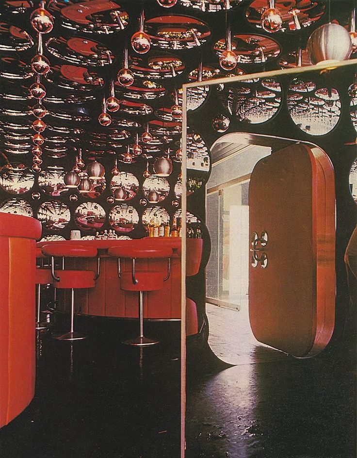 a room filled with lots of red chairs next to a wall covered in hanging lights