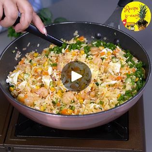 someone is cooking rice and vegetables in a skillet on the stove with a spatula