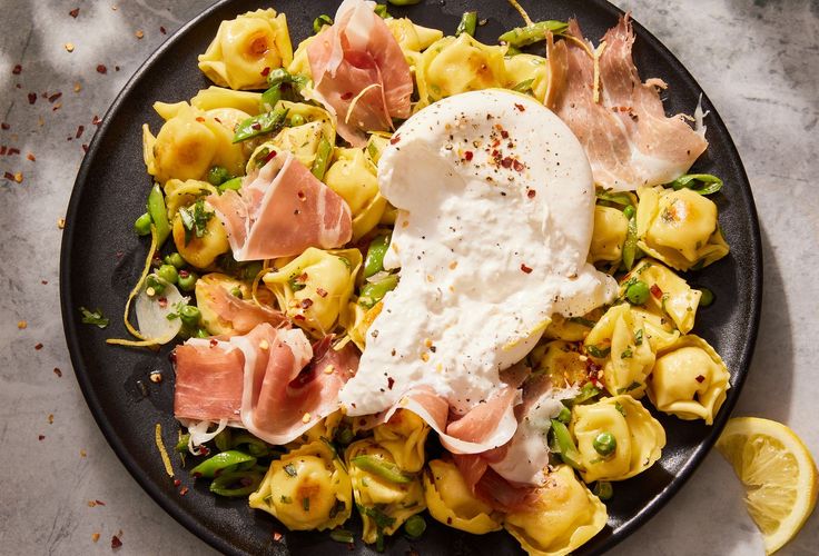 a black plate topped with pasta and an egg