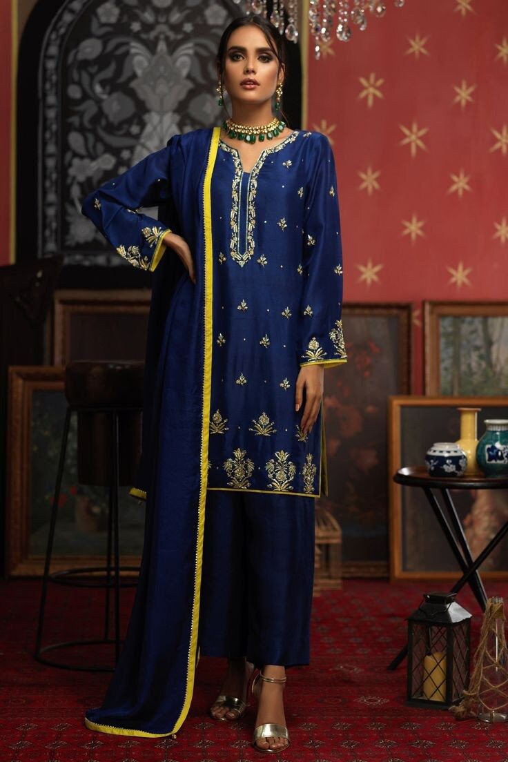 Regal royal blue silk kurta paired with straight palazzo bottoms, creating a sophisticated ensemble Dupatta adorned with vibrant contrast yellow piping along all four sides, enhancing the overall appeal Needle and thread work intricately embellished on the flair of the kameez, sleeves, and neckline for a touch of elegance Delicate pearl and zari detailing further enriching the kameez, adding a luxurious and refined texture Slit sleeves and neckline for a modern and stylish silhouette, blending t Straight Kurta With Pants, Kurta Sets For Women, Zardosi Embroidery, Eid Outfits, Boutique Suits, Indian Wedding Wear, Silk Kurta, Pakistani Dress, Suit Design