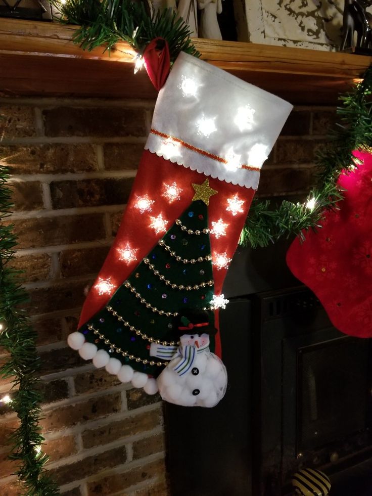 two christmas stockings hanging from a mantel with lights and snowman decorations on them