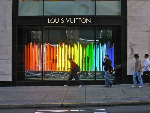 two men walking past a louis vuitton store on the street in front of it