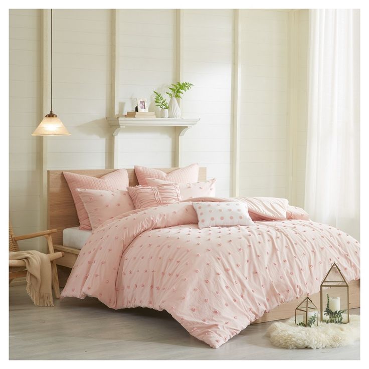 a bed with pink comforters and pillows in a room