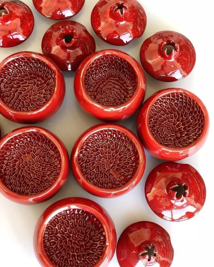 a group of red vases sitting on top of a white table