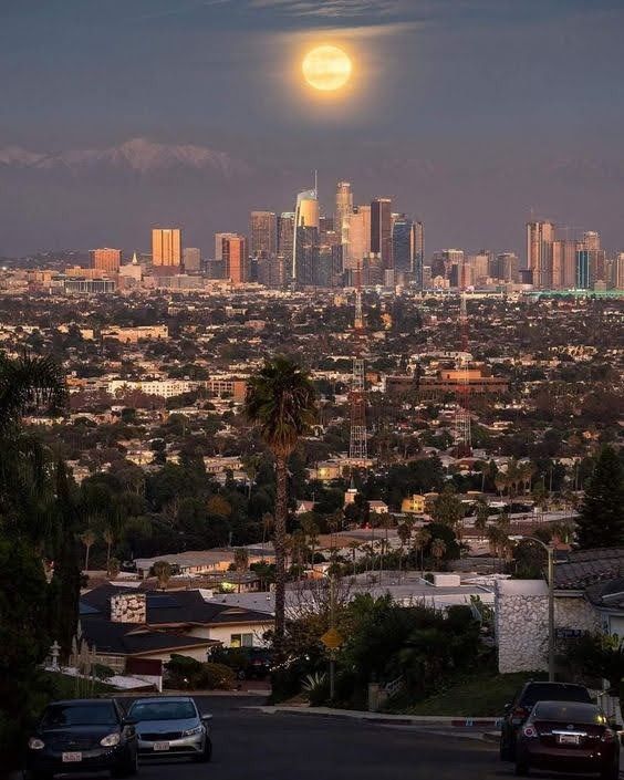 the full moon is setting over a city