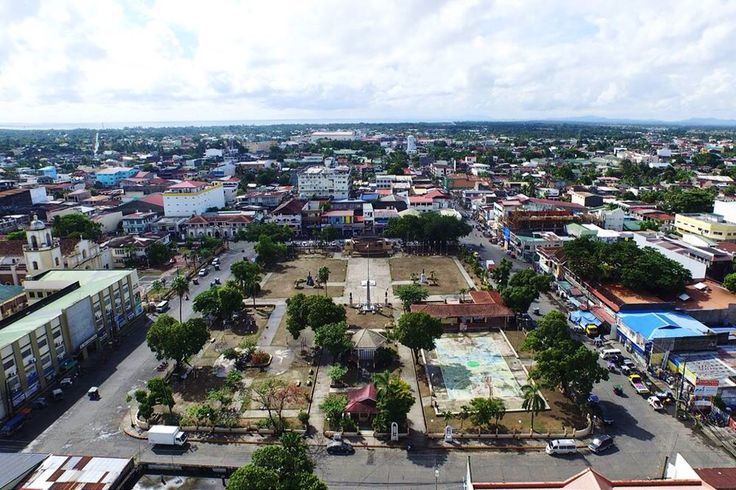 an aerial view of a city with lots of buildings and trees in the foreground