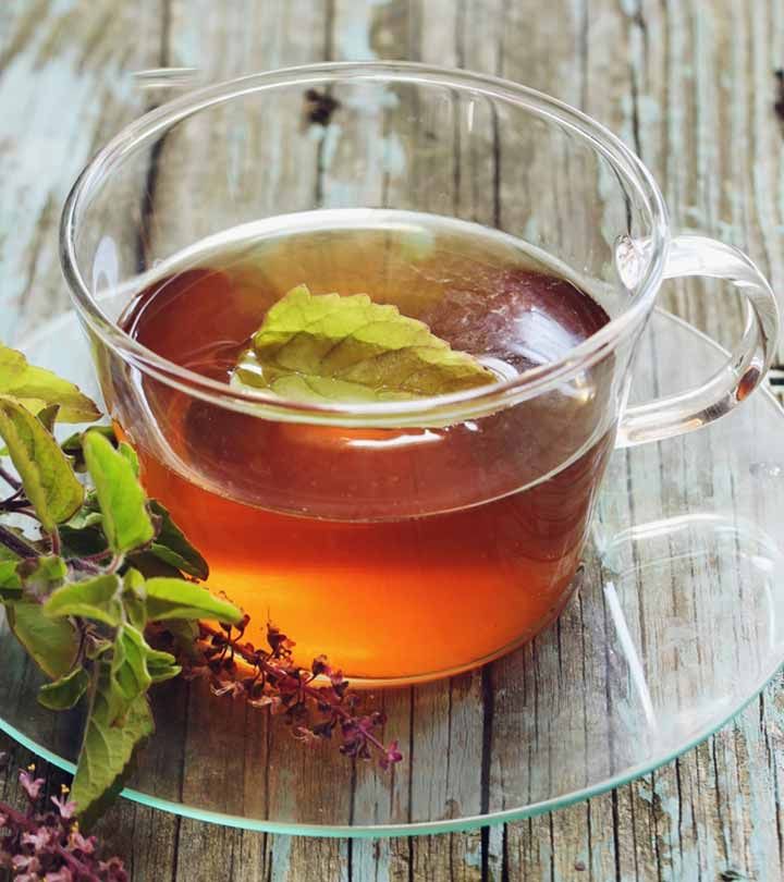 a glass cup filled with green tea next to flowers