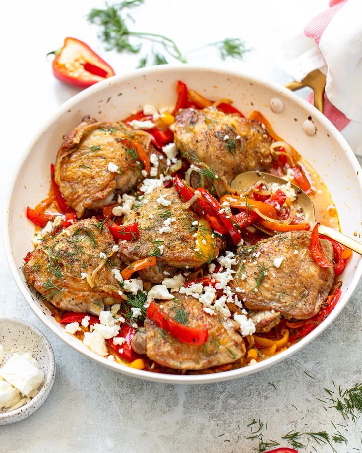 a white bowl filled with meat and vegetables on top of a table next to garlic