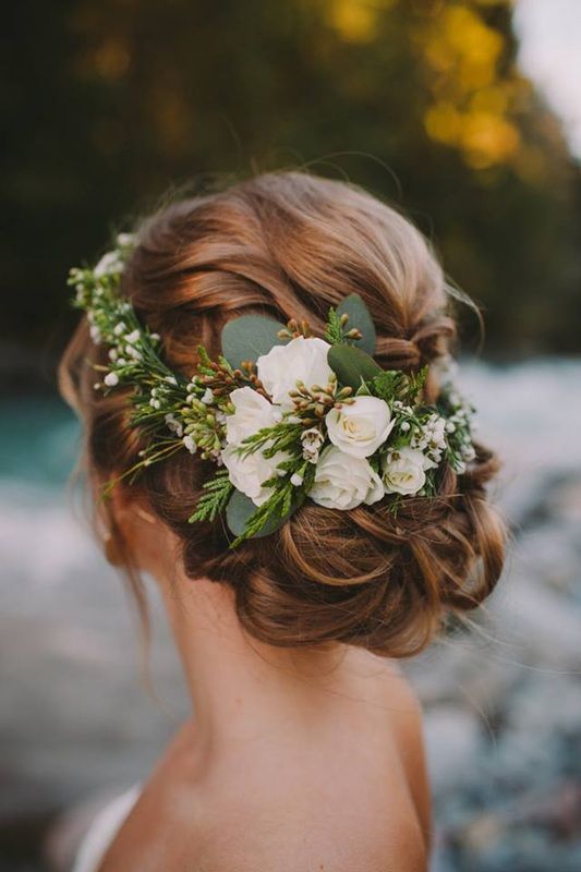 a woman with flowers in her hair is looking at the water and rocks behind her