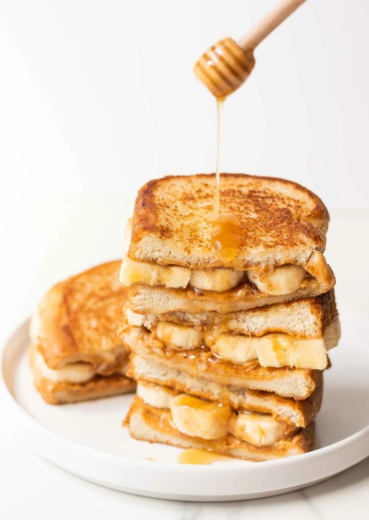 a stack of grilled cheese and banana sandwiches with honey being drizzled over them