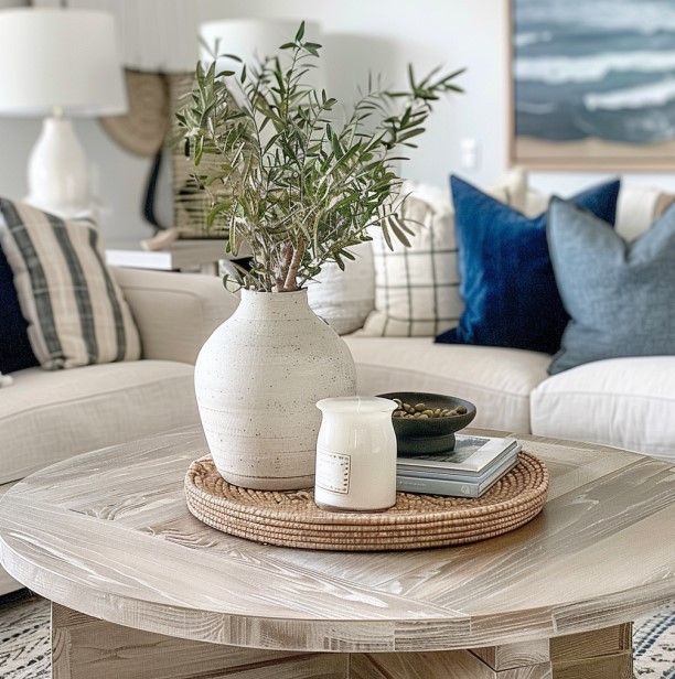 a living room with white couches and blue pillows on the coffee table in front of it