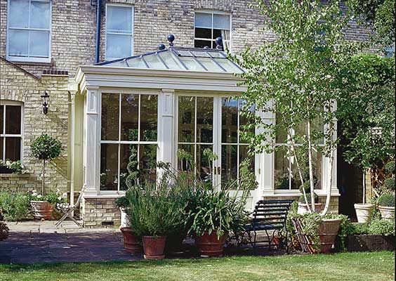 an orangery with potted plants in front of it