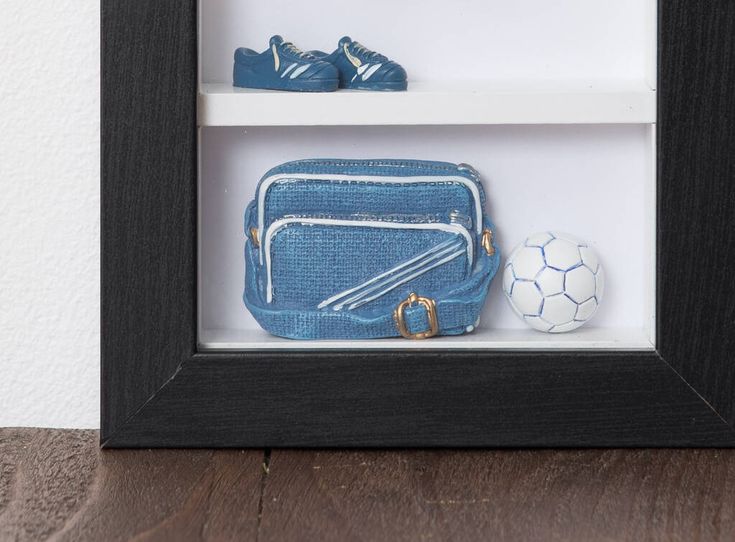 there is a blue purse and soccer ball in a shadow box on the table next to it