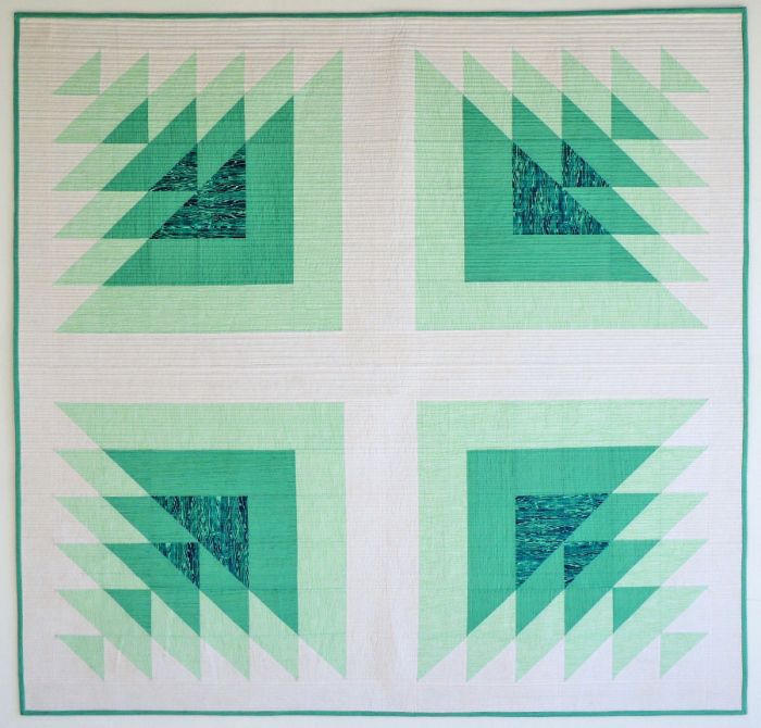 a green and white quilt with triangles on it