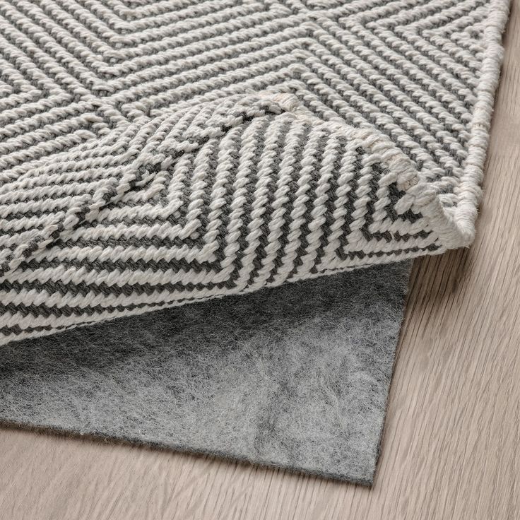 a close up view of the grey and white herringbone rug on top of a wooden floor