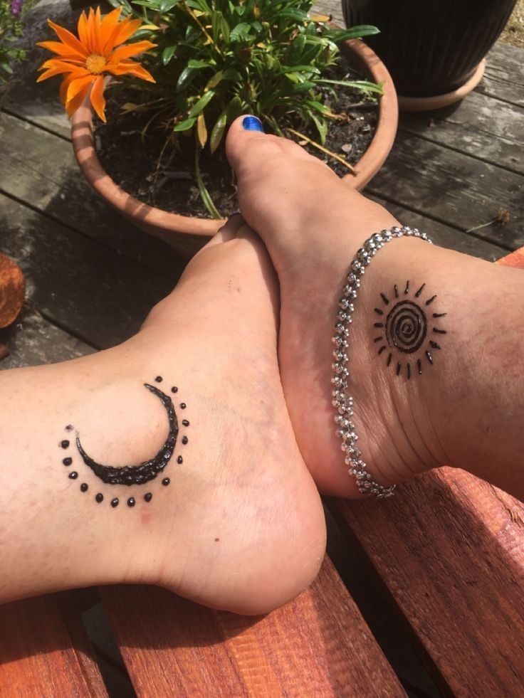 two people with tattoos on their legs sitting on a wooden bench next to each other