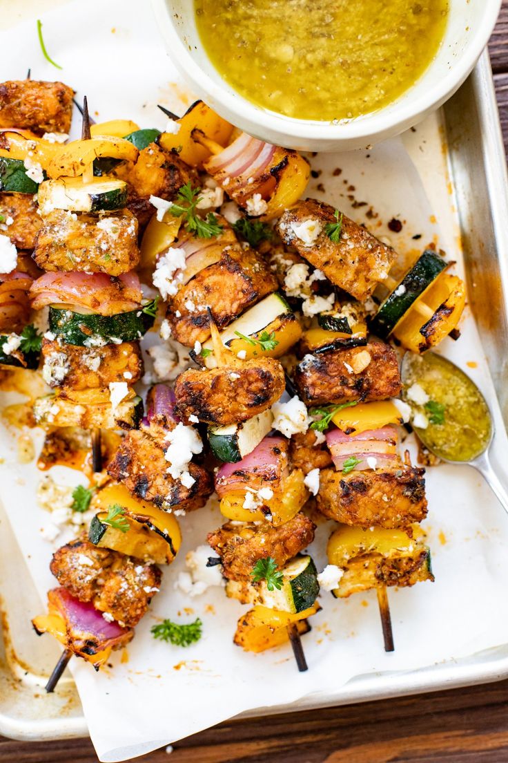 grilled chicken skewers with pesto and feta cheese on a tray