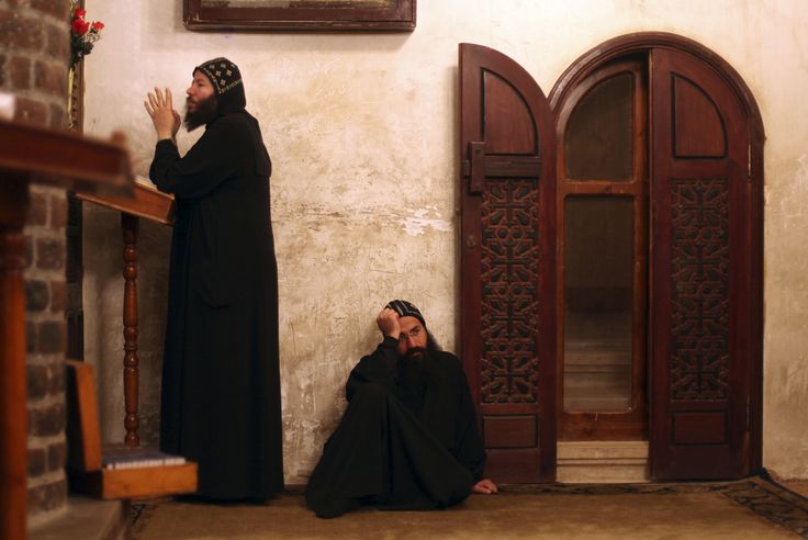 two men sitting on the ground in front of a doorway