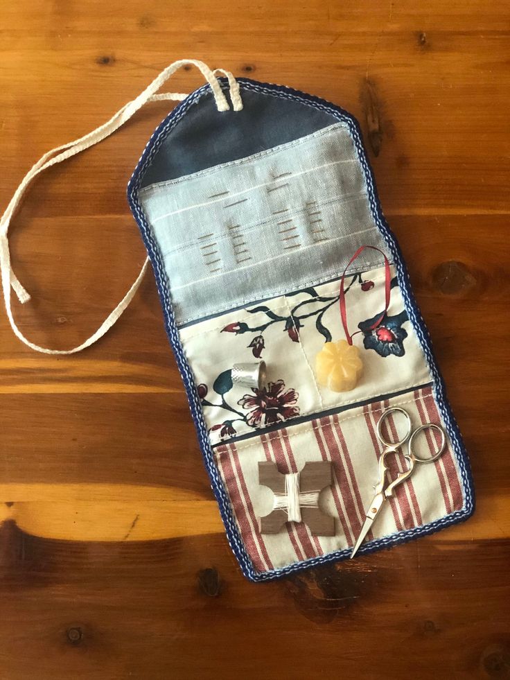 an old purse is sitting on a wooden table with scissors and other items in it