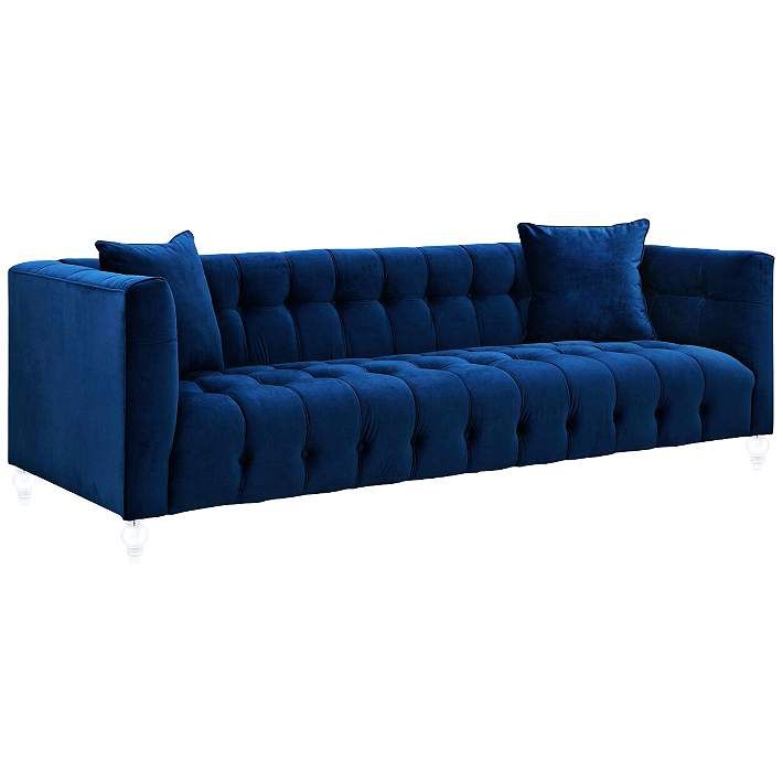 a blue velvet sofa with two pillows on the back and one arm facing away from the camera