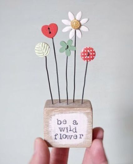 a hand holding a small wooden box with flowers in it and the words be a wild flower