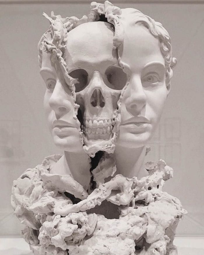 a white sculpture with multiple faces and hair on display