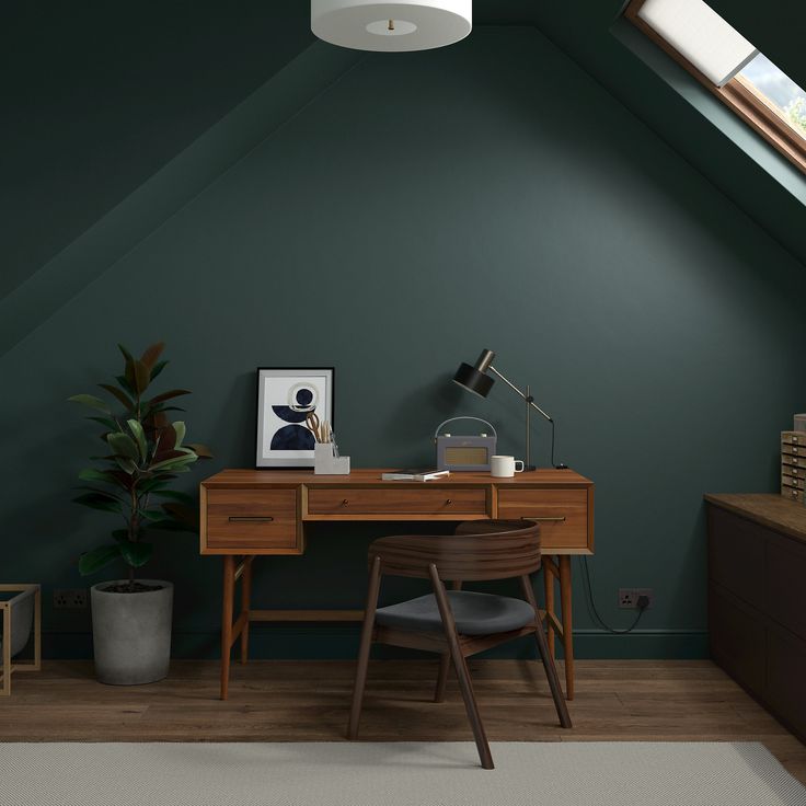 a room with green walls and a wooden desk in the corner next to a window