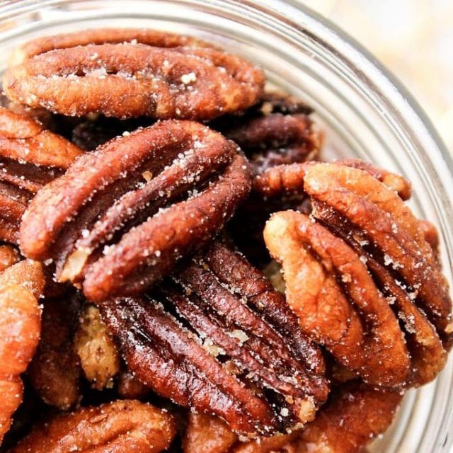 a glass bowl filled with pecans on top of a table