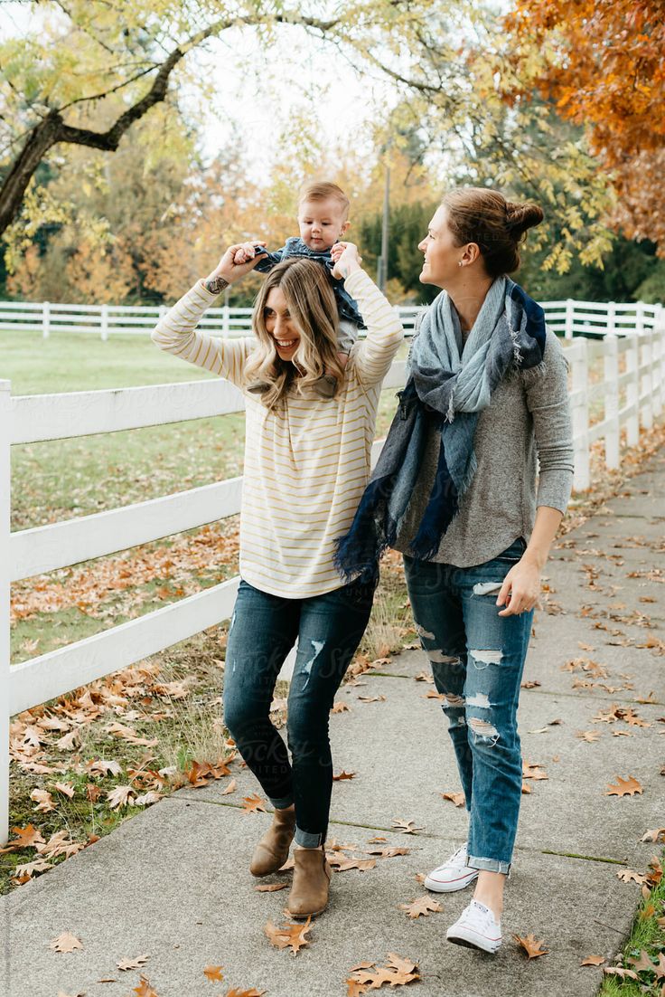 a mother and her child walking down the sidewalk in front of a white picket fence