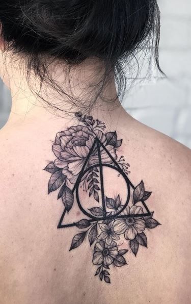 the back of a woman's neck with flowers and a triangle tattoo on it