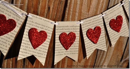 some red hearts are hanging from a string on a wooden fence, with the words love spelled