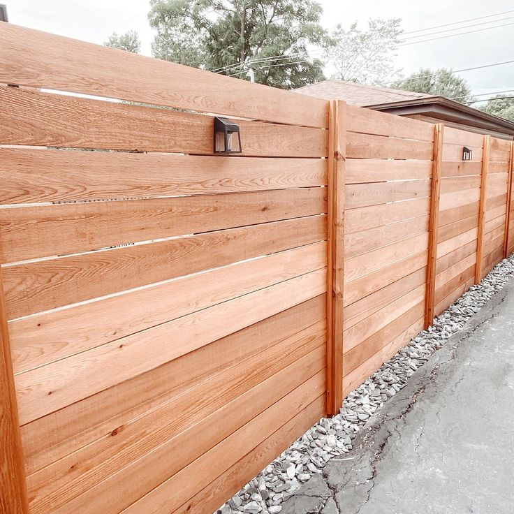 a wooden fence is lined with gravel and rocks