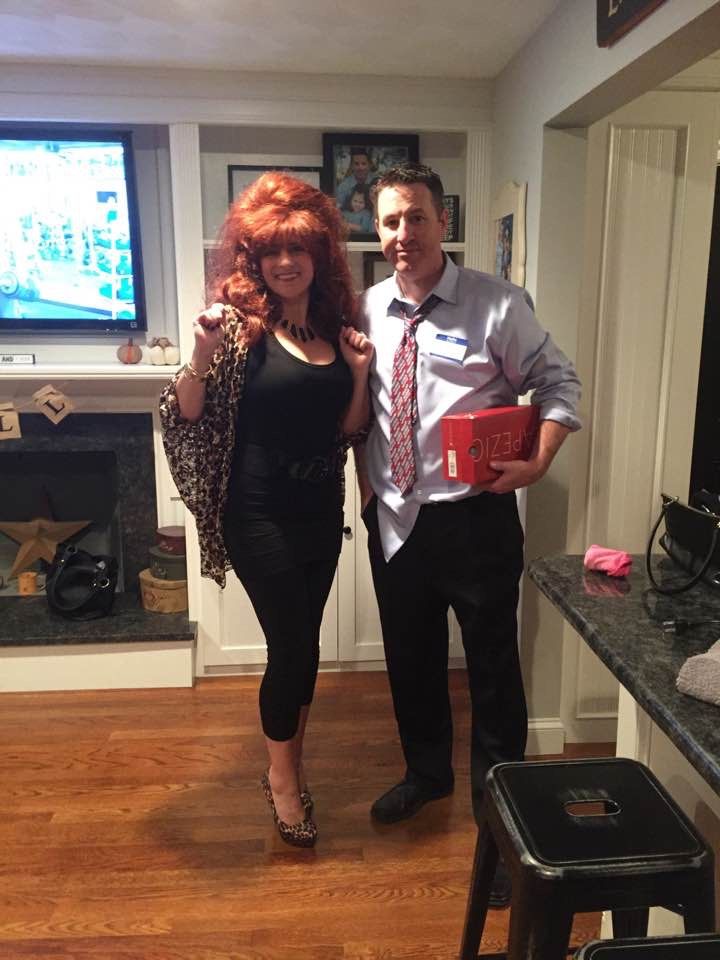 a man standing next to a woman in a living room holding a red present box