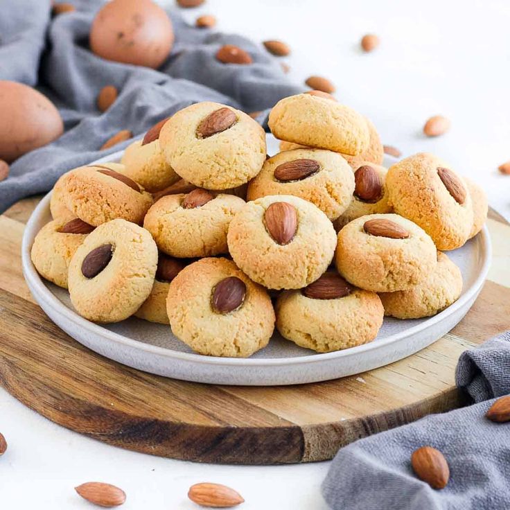 almond cookies on a plate with nuts scattered around