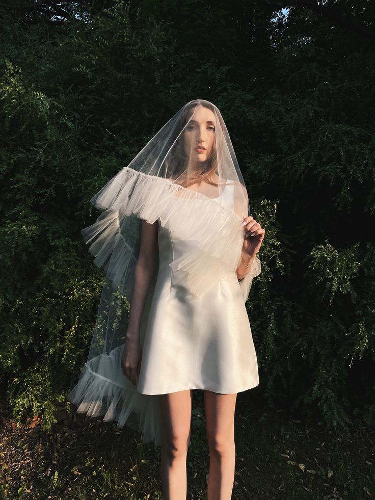 a woman in a white dress with a veil on her head is posing for the camera