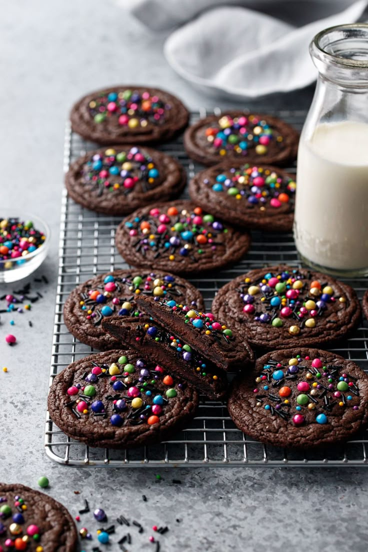 chocolate cookies with sprinkles on a cooling rack next to a glass of milk