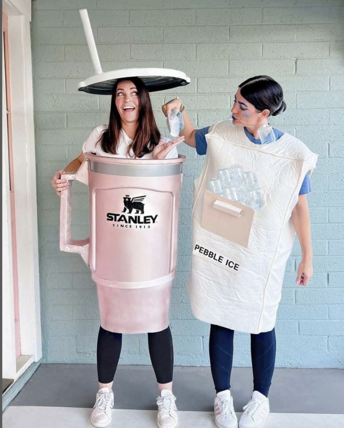 two women dressed in costumes standing next to each other and one holding a plastic bottle