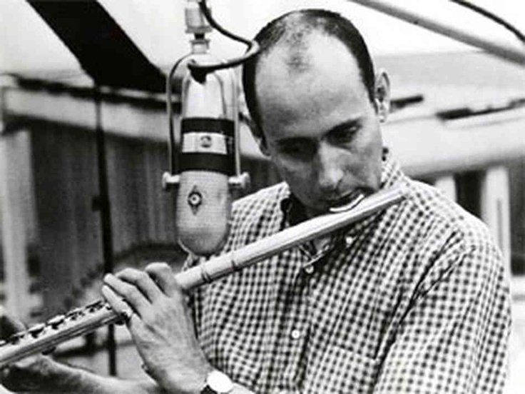 a man is playing the flute while wearing a hat