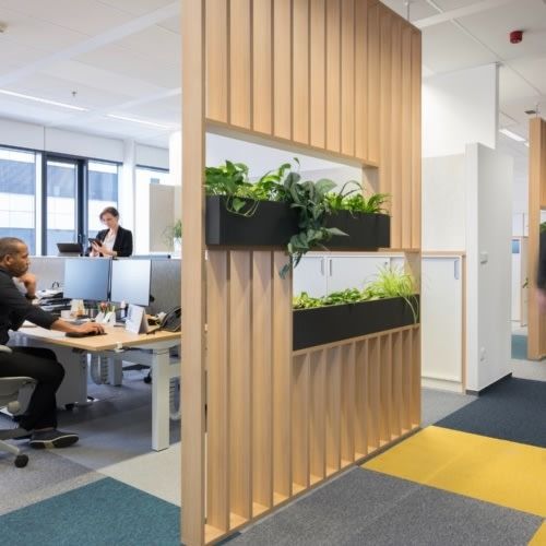 two people working in an office with plants on the wall