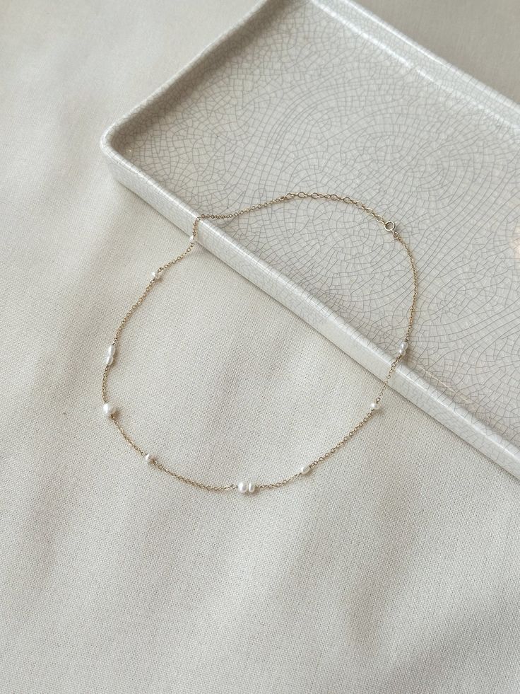 This delicate mixed Pearl chain necklace is minimal yet unique and puts a modern twist on a classic Pearl necklace! The genuine white Pearls are unevenly distributed on the sparkly dainty chain. This is a beautiful piece that is sure to get you many compliments! * 14K Gold Filled or 925 Sterling Silver chain & dainty spring clasp * Choose from 16"-18" or 18"-20" length * 3mm-5mm Freshwater Pearls * 14/20 gf or 925 stamp for authenticity * Made with 100% hypoallergenic materials See all Pearl Jew Dainty Single Strand White Chain Necklace, Dainty White Single Strand Chain Necklace, Delicate 14k Gold Necklaces For Everyday Elegance, White Dainty Necklace For Everyday, Dainty White Necklace For Everyday Elegance, White Minimalist Necklace For Everyday Elegance, Minimalist White Necklace For Everyday Elegance, Minimalist Pearl Necklace With Satellite Chain As Gift, Minimalist Pearl Chain Jewelry For Everyday Elegance