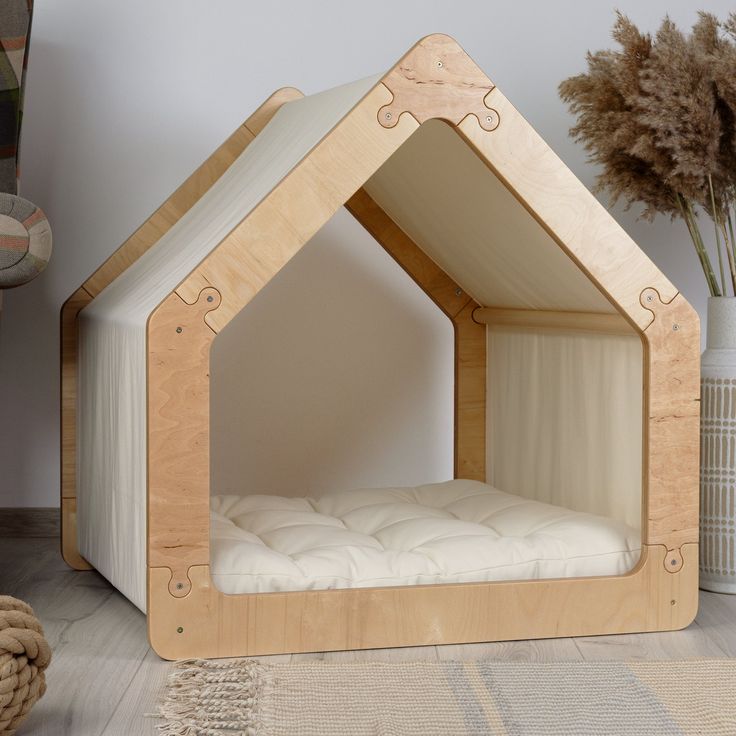 a dog house bed made out of plywood and white fabric with a mattress in the middle