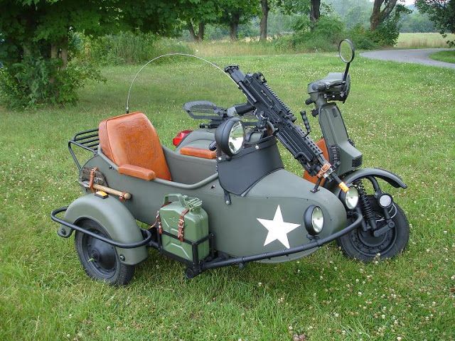 an army motorcycle with a sidecar and luggage strapped to the back is parked on grass