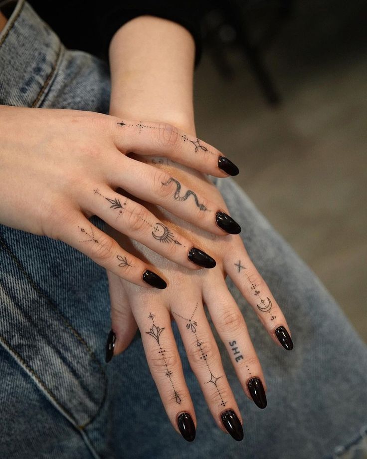 a woman's hand with tattoos on it and two fingers that have writing on them