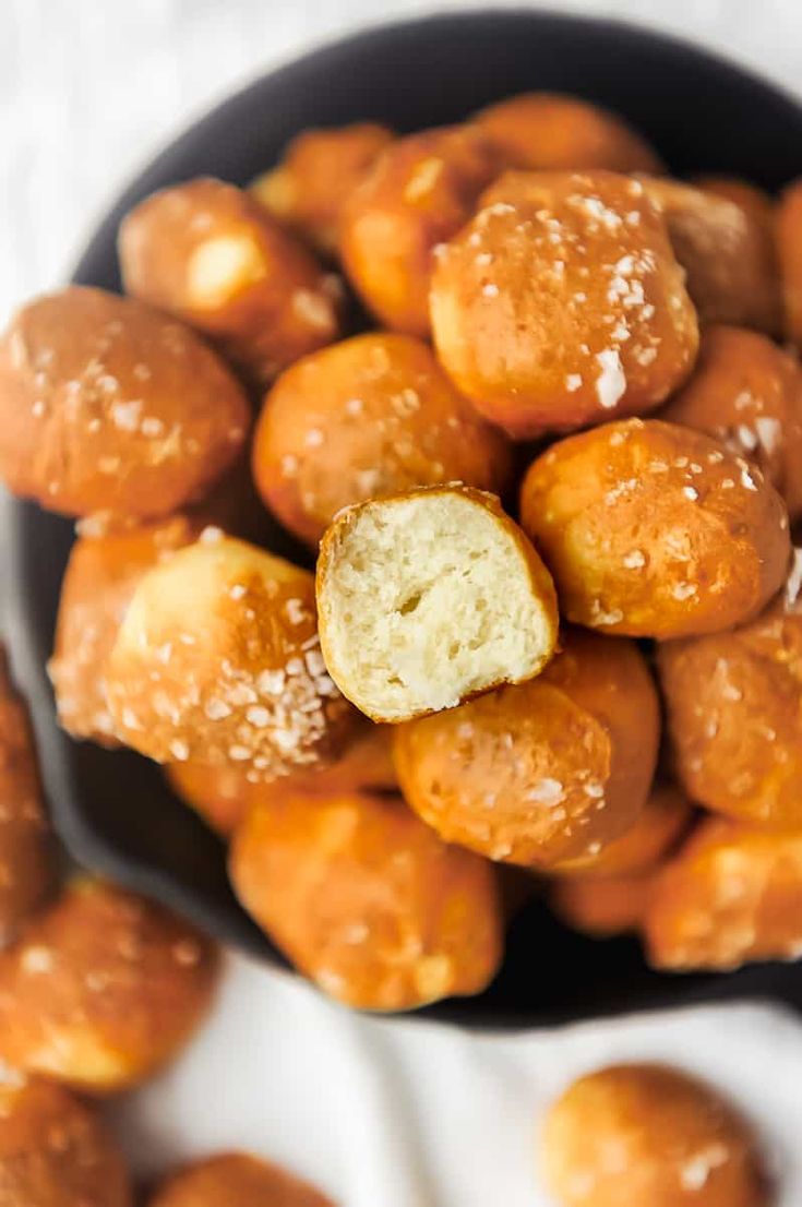 a bowl filled with sugar coated doughnuts on top of a white table cloth