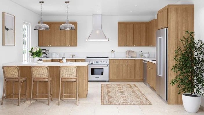 a large kitchen with wooden cabinets and white counter tops, an island in the middle is surrounded by bar stools